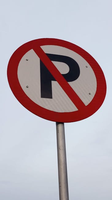 A circular no parking sign with a red border and a black letter 'P' crossed out by a red diagonal line, mounted on a metal pole against an overcast sky. The sign indicates restrictions on parking in the area, which may relate to street access considerations during house removals or furniture transport. Such parking restrictions are relevant for planning vehicle access during home relocation services offered by Man with Van Slade Green, ensuring smooth loading and unloading processes at residential properties in Slade Green. Proper understanding of parking regulations helps avoid move-day fines and facilitates efficient logistics for moving and packing tasks.